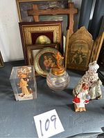 Full lot showing framed pictures, jar with cross lid, resin statue, and two ceramic figurines