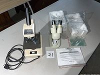 Overview of both microscopes placed on table with accompanying accessories and packaging foam for one microscope