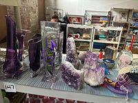 Overview of four purple glass vases at left and amethyst geodes at center