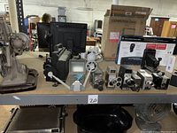 Reel to reel equipment and various vintage 8mm movie cameras displayed on a shelf.