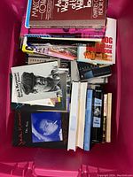 Red bin filled with various vintage books including notable titles by Jack Kerouac and others, showing a mix of hardcovers and paperbacks.