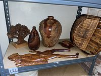 Full view of assorted wood pieces including burl vases, tree sculpture, basket, and wooden plaque on shelf.