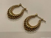 Two ribbed hoop earrings laid flat on white background