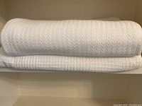 Two folded white blankets stacked on a shelf