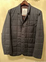 Front view of dark grey quilted men's coat on hanger