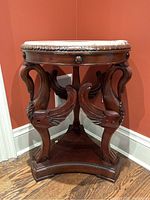Side view of the carved dark mahogany wood pedestal base with three swans supporting the top.
