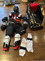 Overhead view of all laid out items: helmet, shoulder pads, gloves, pants, shin pads, socks, bag