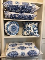Quilt set folded and pillows arranged on shelf showing color and pattern