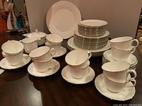 Photo showing cups and saucers arranged in front and plates stacked in back, along with cream and sugar bowl.
