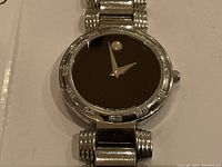 Close-up of watch face and bezel showing black dial text and diamond accents