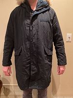 Front view of the black Rag & Bone men's slim fit winter coat parka, showing button closure and coyote fur hood collar.