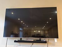 Front view of wall-mounted 76" TV above shelf