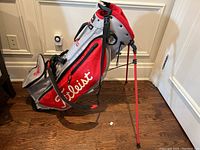 Front view of golf bag showing red and grey panels and Titleist logo
