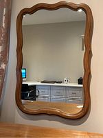 Front view of the rectangular wooden wall hanging mirror showing the scalloped wavy edge frame and clear reflective mirror glass.