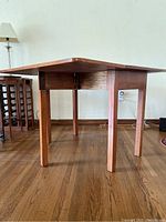 Full side view of the antique table highlighting the legs, apron, and drop leaf sides in lowered position.