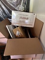 Cardboard box with new Miha 2 tier clear organizer in packaging and white metal parts inside the box