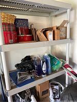 Shelf with cleaning supplies, old Christmas tins, brown paper bags, and small tools.