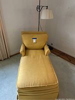 Yellow mid century modern chaise lounge showing seat, back cushion, armrests, and textured yellow upholstery.