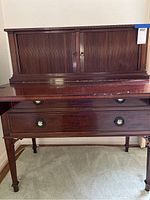 Front view of antique mahogany writing desk showing tambour doors and lower drawers