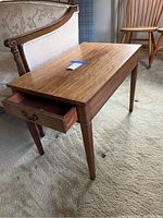 Side view of wooden end table showing single drawer pulled out and tapered legs.