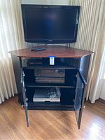 Corner entertainment center with 36-inch Insignia TV mounted on top, glass door cabinet below houses stereo components