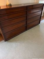 Full view of the mid century modern mahogany dresser with eight drawers in a carpeted room.
