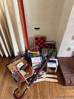 Photo showing a collection of games, felt squares, umbrella, and hangers grouped on the floor near a wall and curtain.