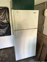 Front view of white Whirlpool top-freezer refrigerator, showing appliance exterior and handle details.