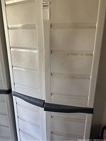 Closed view of white plastic utility cabinet with black handles