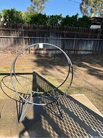 Front side view of metal log holder against outdoor fence and yard area.