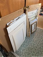 Stacks of mats, foam core boards, and large sheets of watercolour paper leaning against a door, with large paper backing and packing materials.