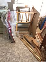 Overall view of artist wood supply stand with mats and frames leaning against wall, several sheets of art paper and backing boards included.