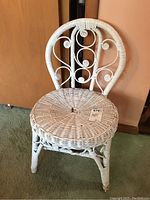 Front view of the painted white rattan and wicker slipper chair showing curled rattan scroll design on backrest and woven wicker seat.