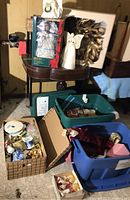 Photo shows multiple Christmas decorations including boxed fiber optic angel, gold wreath, white angel figurine, and several plastic totes filled with ornaments and ribbon rolls.
