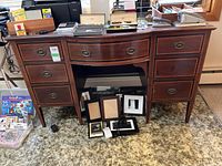 Front view of wood desk with six drawers and metal pull handles, some wear and detached drawer pull visible