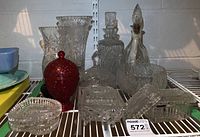 Wide view of the lot with clear crystal decanters, vases, lidded dishes and the red Avon lidded bowl.