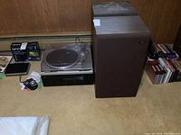 Wide shot showing pair of brown Akai speaker cabinets, Technics SL-Q202 turntable (with dust cover) and Yamaha amplifier unit on carpet