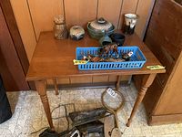 Full view of wood table with assorted pottery and mini animal figures in a plastic tray.