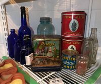 Photo of vintage tins and cobalt bottles on white wire shelf showing detailed labels and sizes