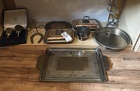 Wide shot of all silverplated items showing goblets, trays, and lidded serving dishes on wooden floor