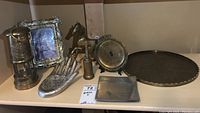 View of the lot including brass sailing lantern, horse sculpture, coin toss hand dish, metal tray, picture frame, and compass