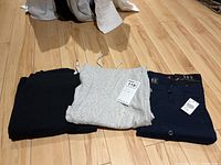 Three pairs of pants laid side by side: black Joe Fresh sweatpants, light grey sweatpants with tags, navy blue cotton pants with tags.