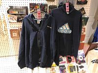 Two men's hoodies displayed hanging, Reebok zip-up on left, Adidas pullover with logo on right.