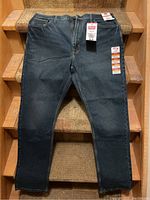 Front view of Wrangler Five Star Premium men’s jeans with original tags laid flat on stairs, color dark blue.