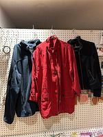 Three jackets hanging on pegboard: black fleece by LL Bean, red cotton jacket, and black stretch jacket.