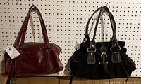 Two purses hanging against pegboard: left purse is burgundy Enzo Angiolini snakeskin textured leather; right purse is black Francesco Biasia suede with leather trim and gold accents.