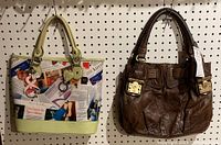 Photo of two purses on pegboard: left is a colorful printed Jeanne Lottie purse with light green base, right is brown Juicy Couture purse with textured leather-like material