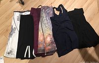 Display of five skirts and one navy blue tank top laid out on wooden floor