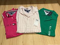 Three Tommy Hilfiger shirts: red button-up with collar discoloration, pink golf shirt with sleeve mark, green golf shirt with tag.