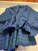 Blue, green, and cream check wool fabric, arranged to show texture and colors.